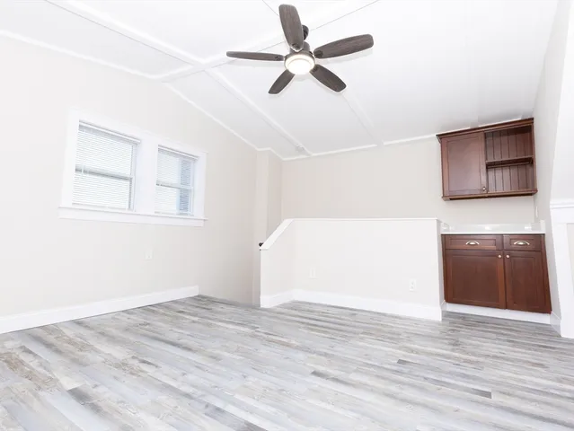 a view of empty room with wooden floor and ceiling fan