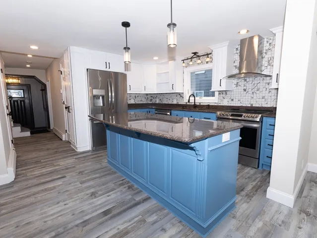 a large kitchen with stainless steel appliances kitchen island granite countertop a stove and a refrigerator