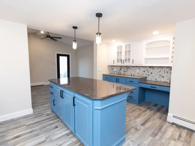 a kitchen with kitchen island granite countertop a sink and a stove