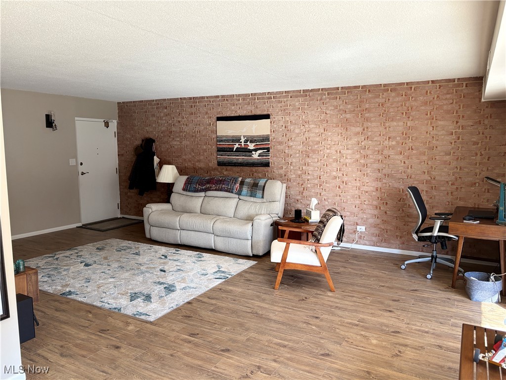 935 Canyon View Road, Unit 104 Northfield, OH 44067 - Photo 3 of 46 Living area featuring baseboards, wood finished floors, brick wall, and a textured ceiling