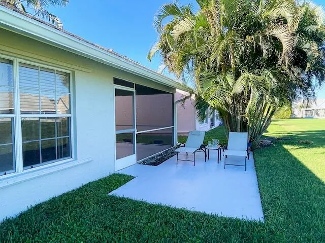 a view of a backyard with table and chairs potted plants and a large tree
