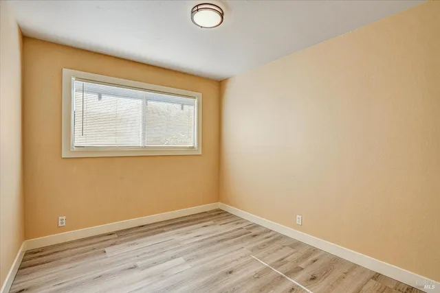 an empty room with wooden floor and a window