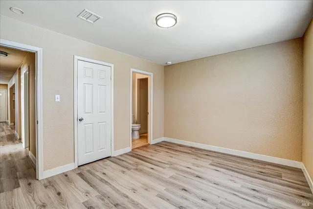 a view of an empty room with wooden floor and closet
