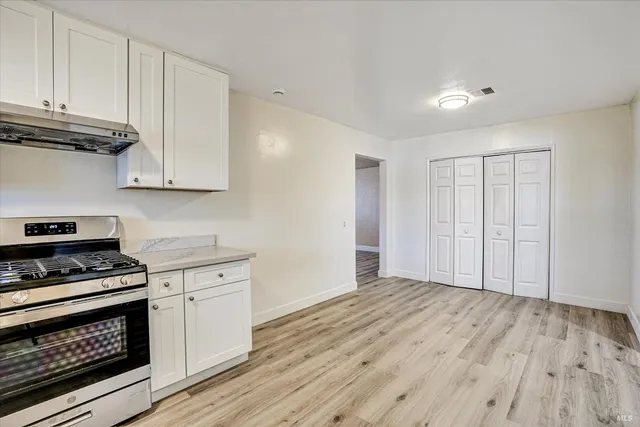 a kitchen with granite countertop a stove cabinets and wooden floor