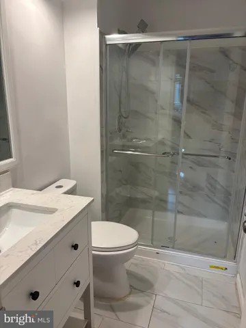 a bathroom with a granite countertop bathtub shower sink vanity and a toilet