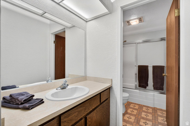 407 South Vasels Road, Unit 24 Brian Head, UT 84719 - Photo 29 of 63 Bathroom with combined bath / shower with glass door, a textured wall, vanity, light flooring, and a textured ceiling