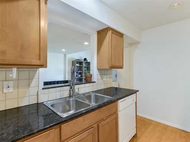a kitchen with granite countertop a sink a stove and cabinets