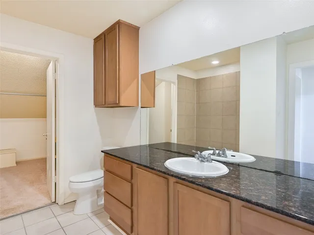a bathroom with a granite countertop sink a toilet and a mirror