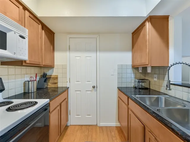 a kitchen with granite countertop a sink stove and cabinets