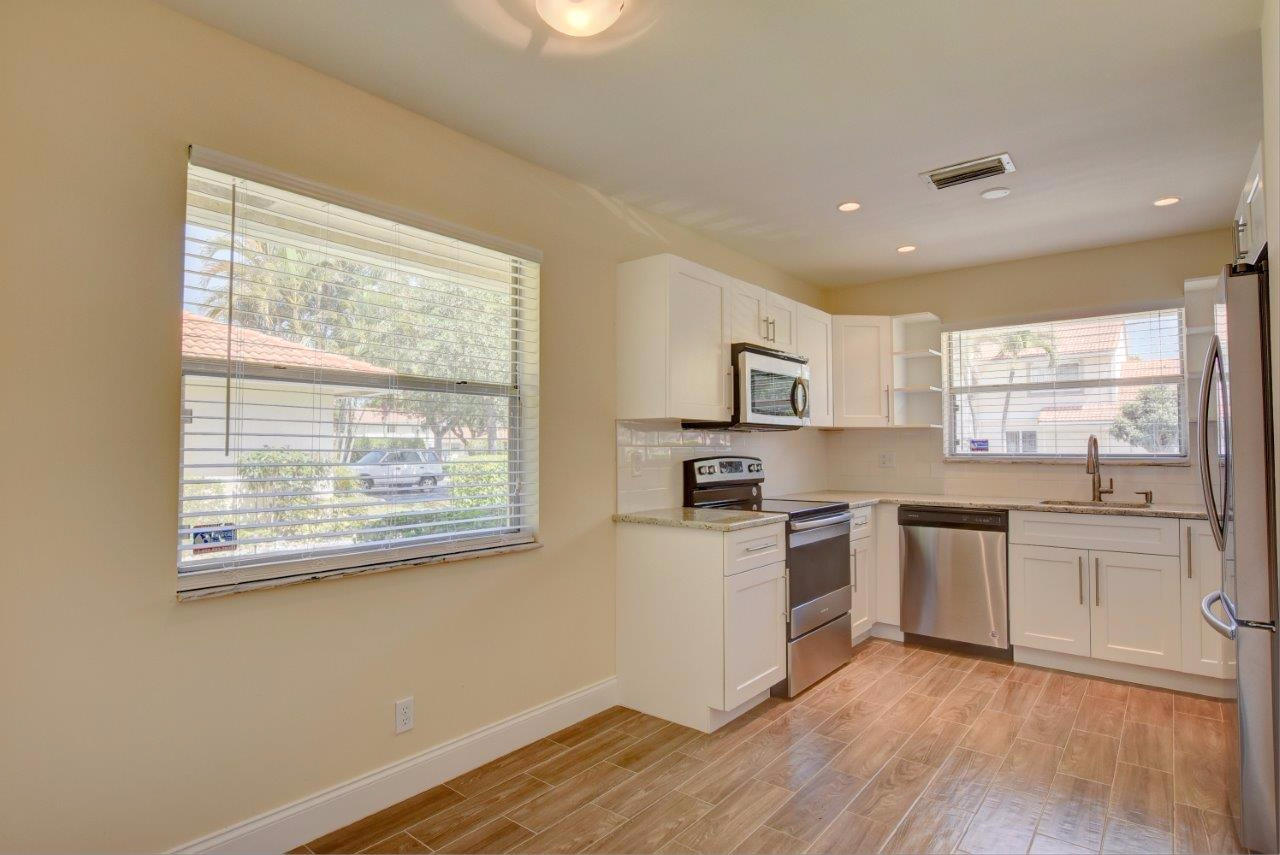 6350 Walk Circle Boca Raton, FL 33433 - Photo 9 of 29 a kitchen with stainless steel appliances white cabinets a wooden floor and a window
