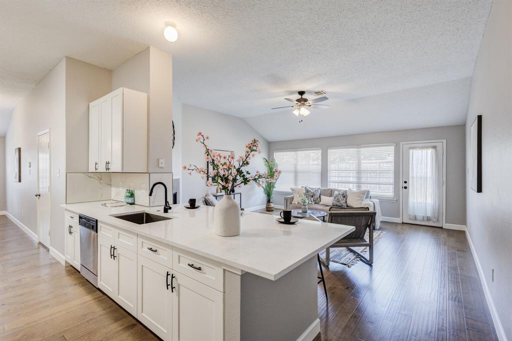 7218 Compass Point Drive Rowlett, TX 75089 - Photo 11 of 30 Kitchen with vaulted ceiling, light stone countertops, white cabinets, light wood-style floors, and dishwasher