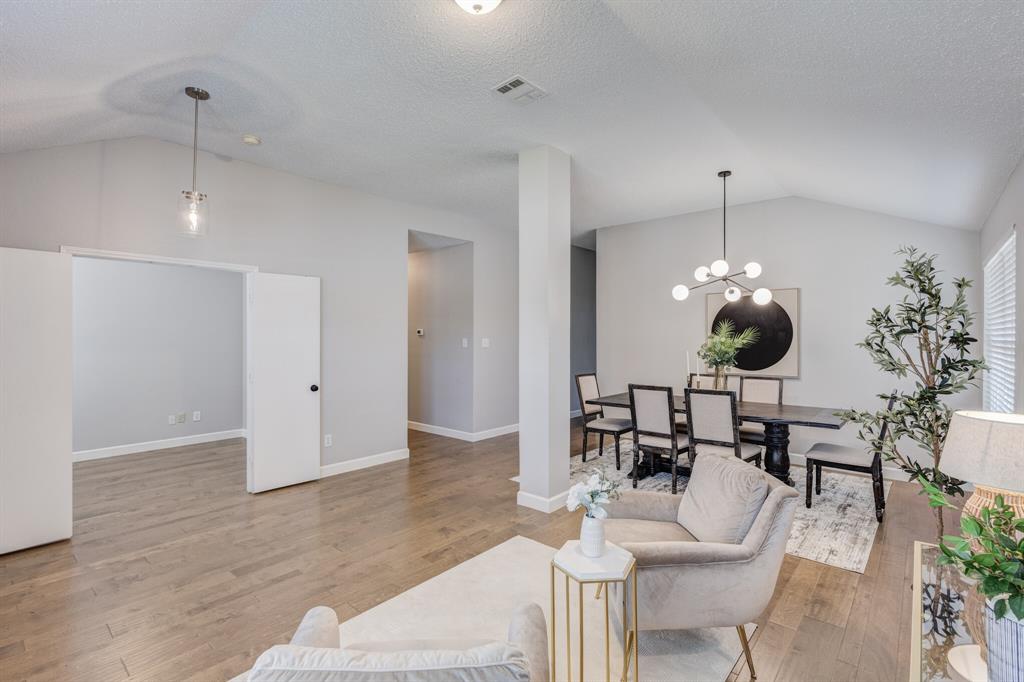 7218 Compass Point Drive Rowlett, TX 75089 - Photo 19 of 30 Living area featuring vaulted ceiling, light wood-style flooring, a chandelier, and a textured ceiling