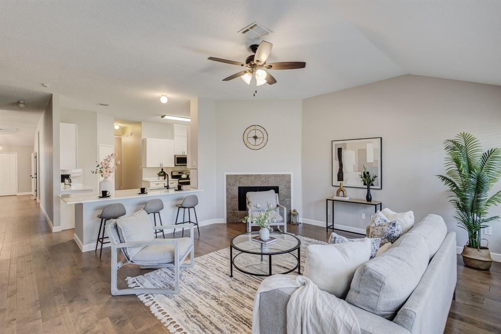 7218 Compass Point Drive Rowlett, TX 75089 - Photo 7 of 30 Living room featuring a ceiling fan, a tile fireplace, dark wood-style flooring, and vaulted ceiling