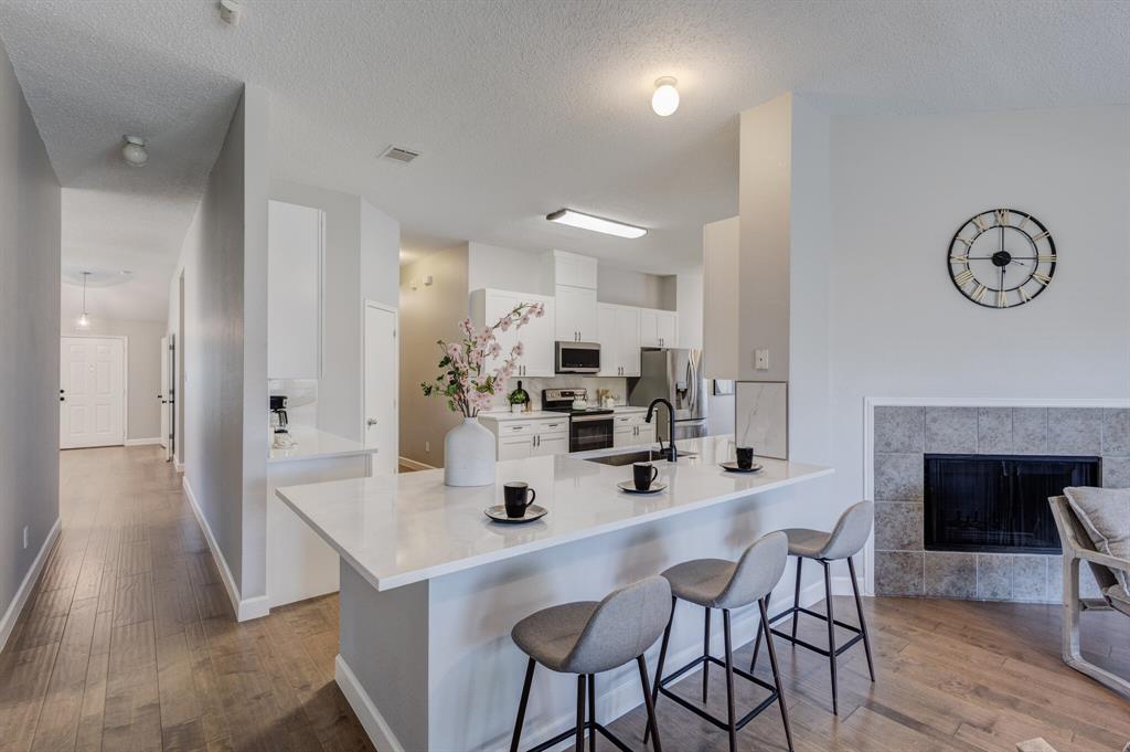 7218 Compass Point Drive Rowlett, TX 75089 - Photo 9 of 30 Kitchen with white cabinets, light wood-style floors, a peninsula, appliances with stainless steel finishes, and a kitchen breakfast bar