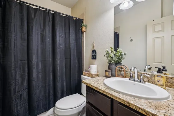 a bathroom with a granite countertop sink toilet and mirror