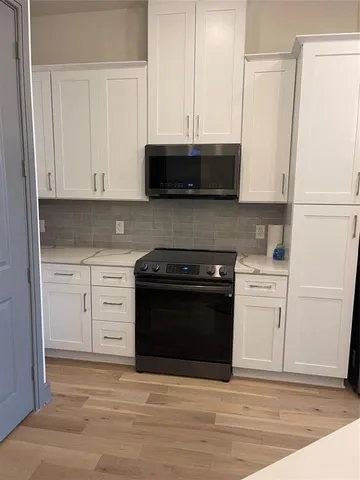 a kitchen with stainless steel appliances white cabinets and a stove a refrigerator with white cabinets