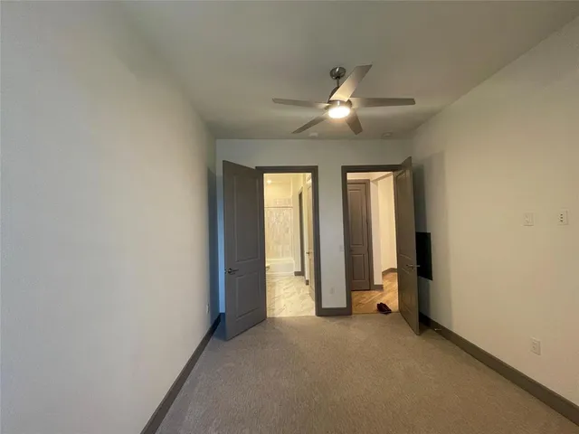 an empty room with closet and a ceiling fan