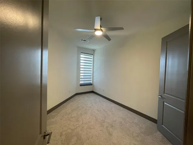 an empty room with windows closet and chandelier fan