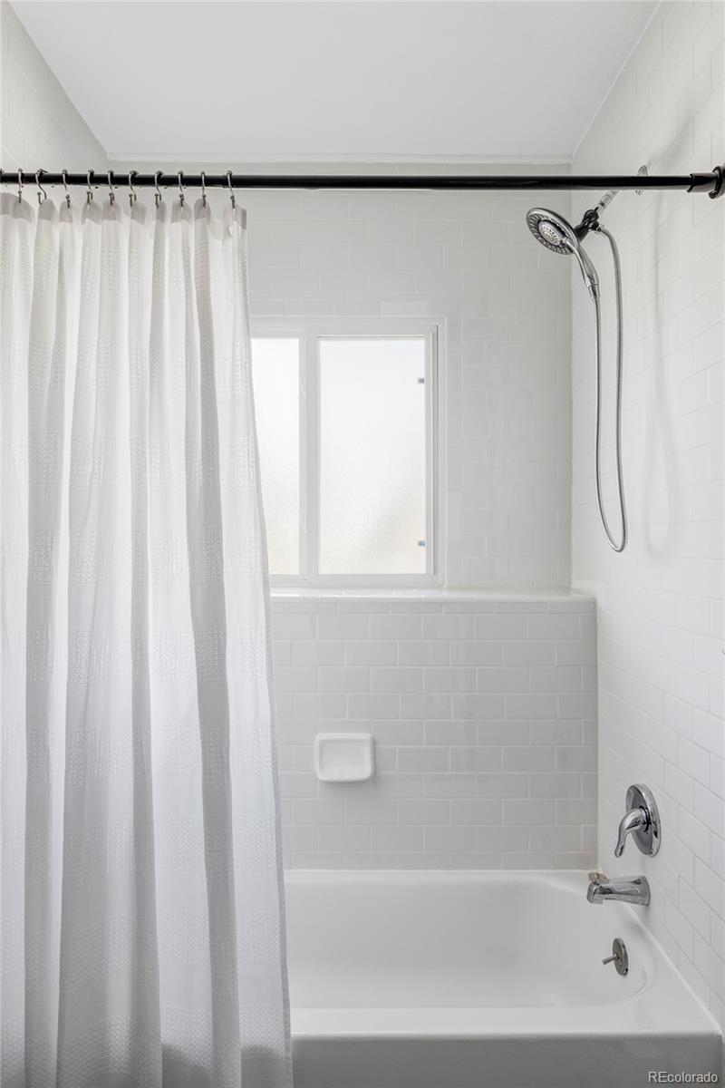 1035 East 10th Avenue, Unit 6 Denver, CO 80218 - Photo 26 of 32 a bathroom with a shower curtain and a bathtub