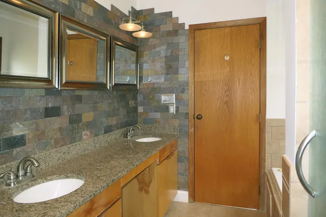 a bathroom with a granite countertop sink a mirror and a shower