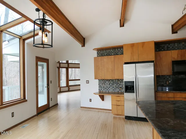 a kitchen with stainless steel appliances granite countertop a refrigerator a oven and white cabinets with wooden floor