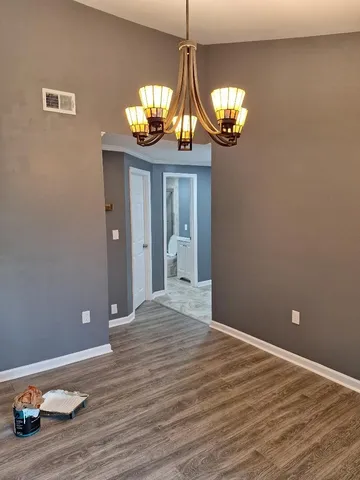 a view of an empty room with a chandelier fan and wooden floor
