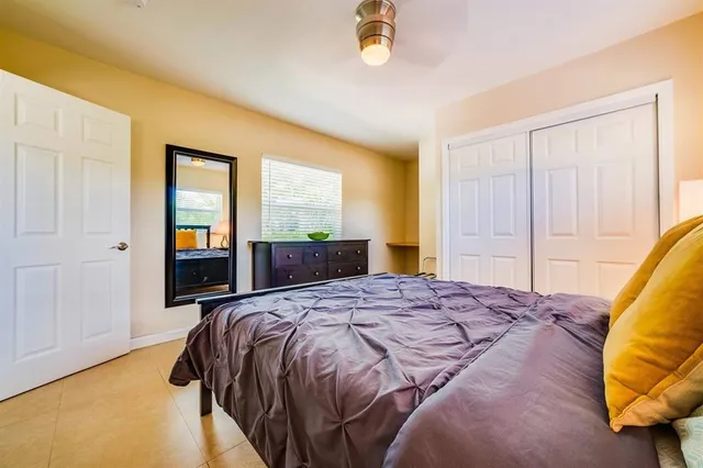 a bed sitting in a spacious bedroom next to a window and a chandelier