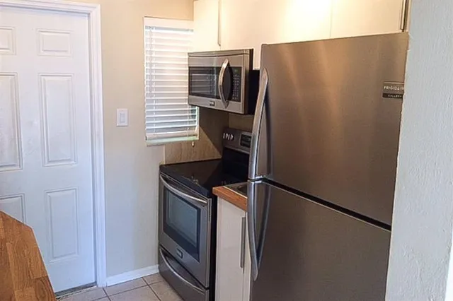 a close view of a refrigerator in kitchen and stainless steel appliances wooden floor