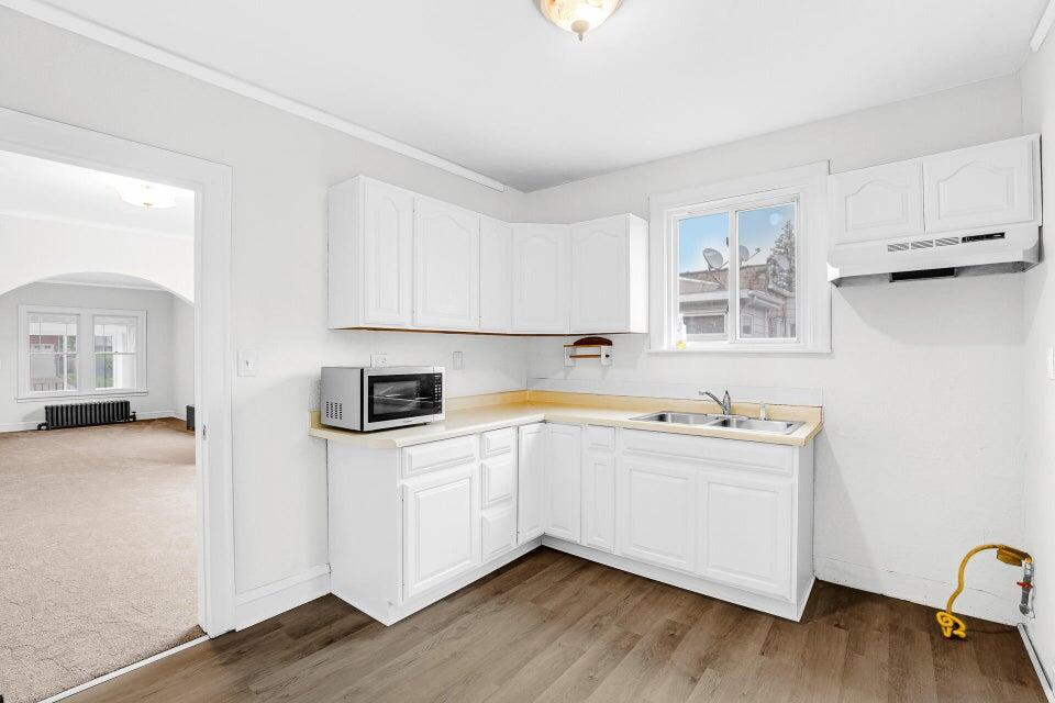 650 119th Street, Unit 1 Whiting, IN 46394 - Photo 11 of 17 a kitchen with stainless steel appliances a sink a stove and white cabinets with wooden floor