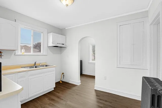 a view of a kitchen with white cabinets and wooden floor