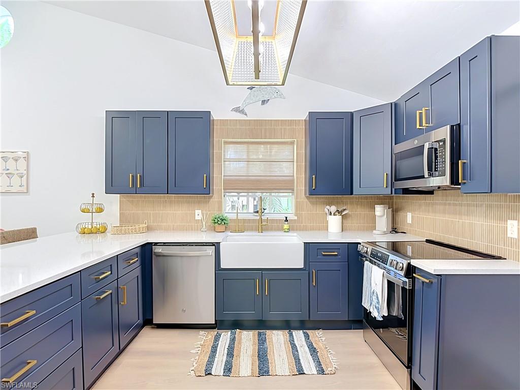 812 102nd Avenue North Naples, FL 34108 - Photo 10 of 33 Kitchen featuring blue cabinetry with gold-finish hardware, white countertops, stainless steel appliances, and a farmhouse sink