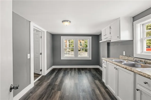 a kitchen with wooden floors white cabinets and sink