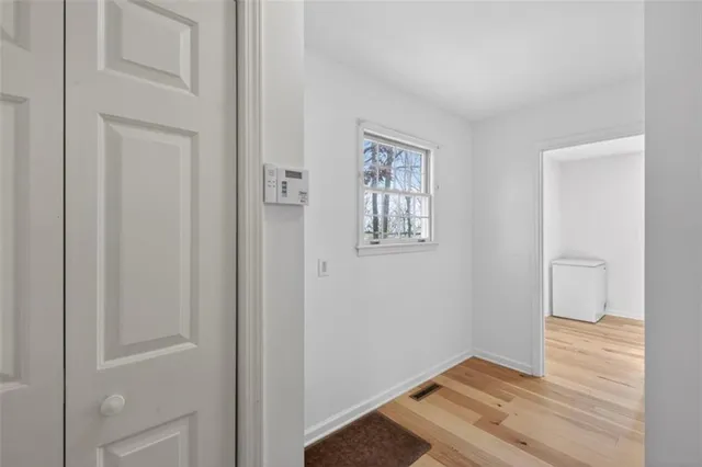 a view of an empty room with wooden floor and a window