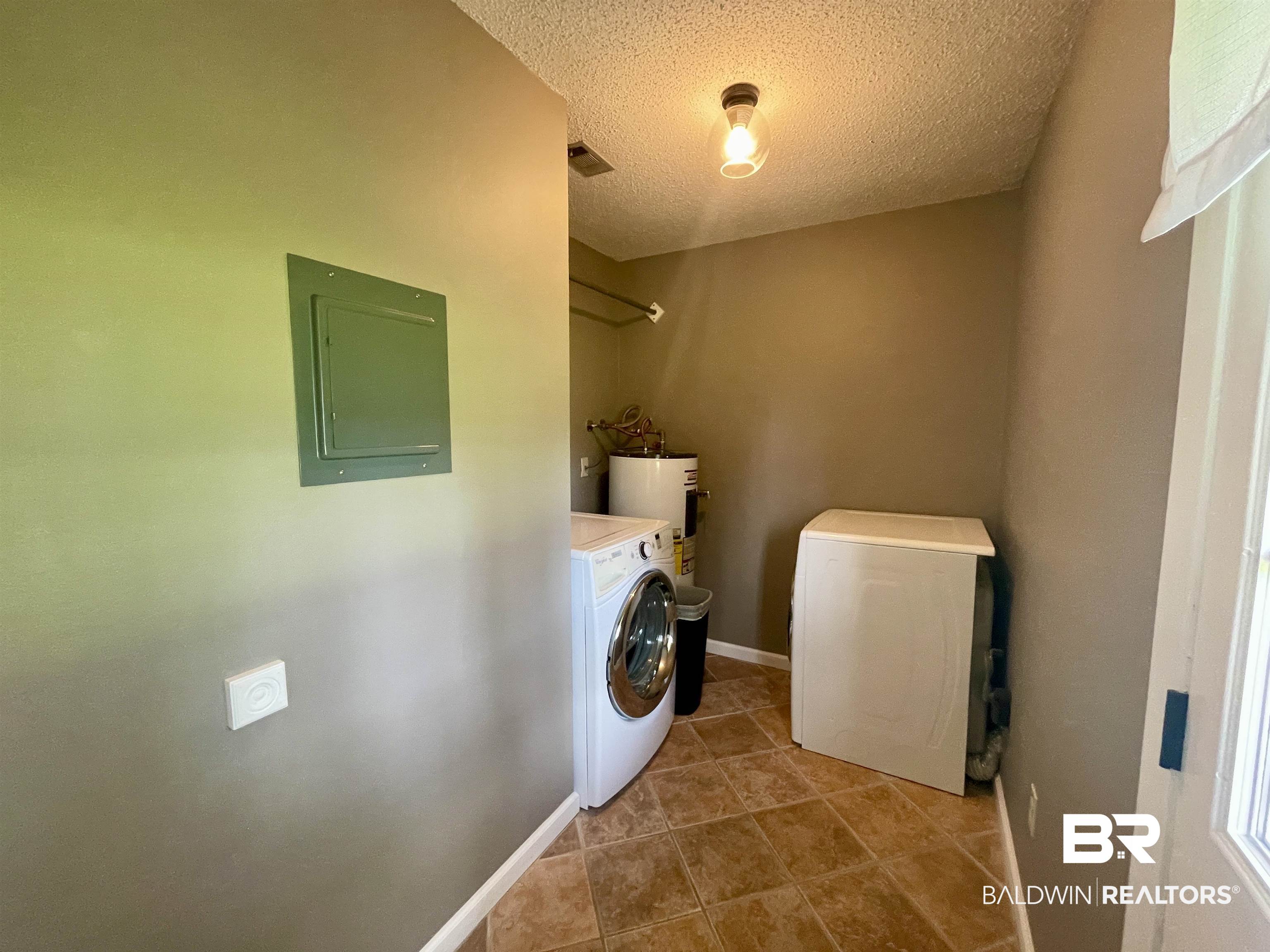 2274 Foshee Road Brewton, AL 36426 - Photo 17 of 23 Laundry room featuring electric panel, a textured ceiling, tile patterned flooring, washer and dryer, and electric water heater