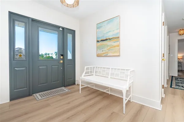 a view of an empty room and bathroom with wooden floor