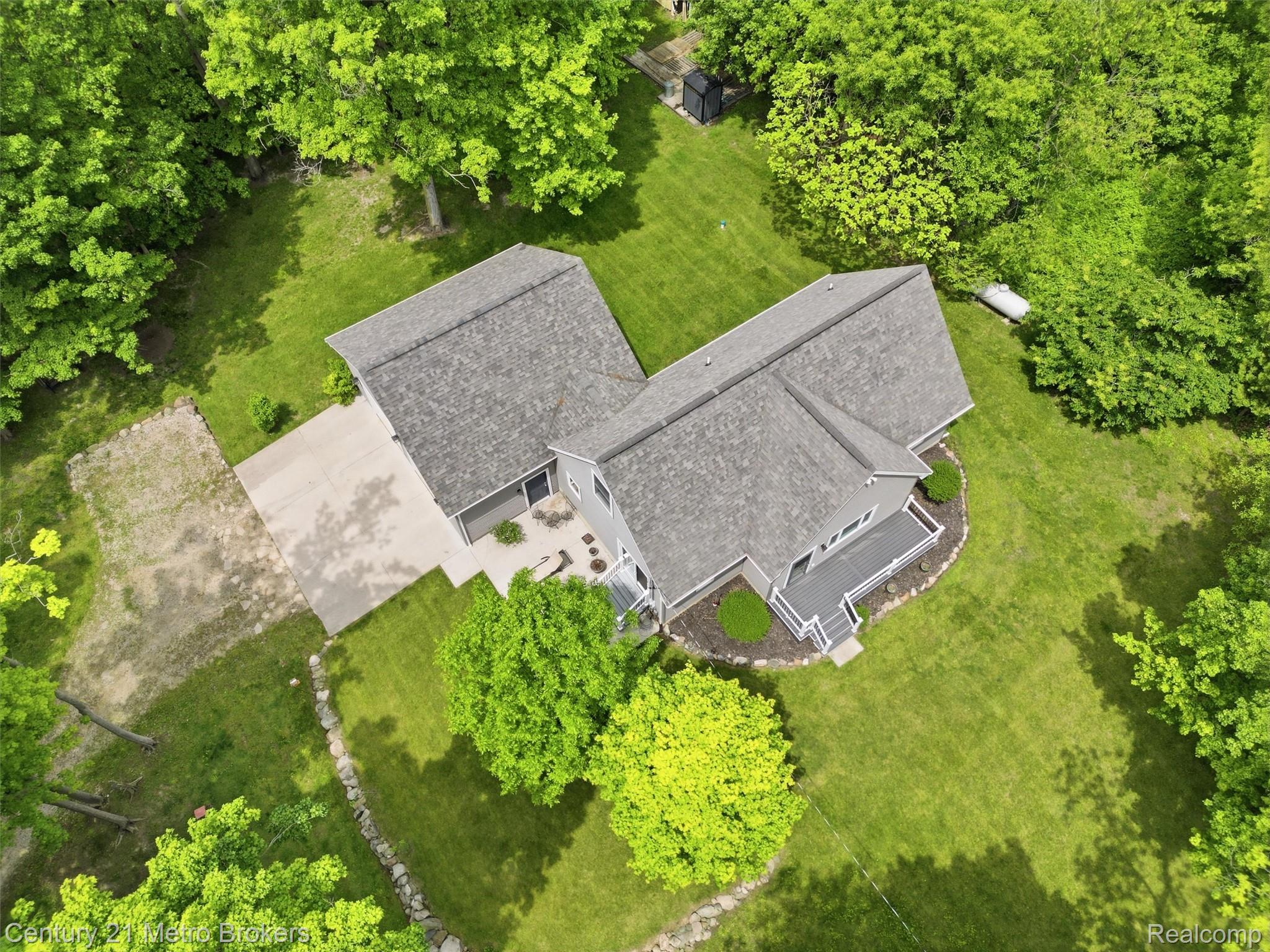 11447 North Latson Road Linden, MI 48451 - Photo 2 of 52 Expansive property featuring a grey-toned residence with a multi-level roofline, a concrete driveway, and a spacious deck