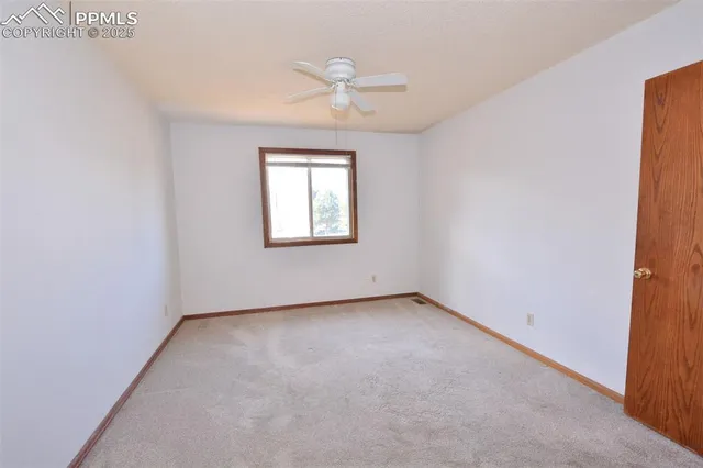an empty room with a ceiling fan and a window