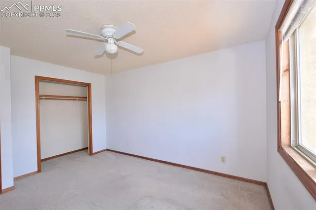 an empty room with windows and fan