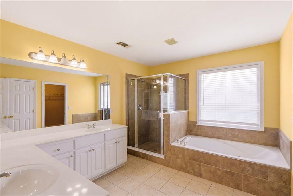 3420 Bulloch Lake Road Loganville, GA 30052 - Photo 37 of 57 a spacious bathroom with a double vanity sink a large mirror and a bathtub