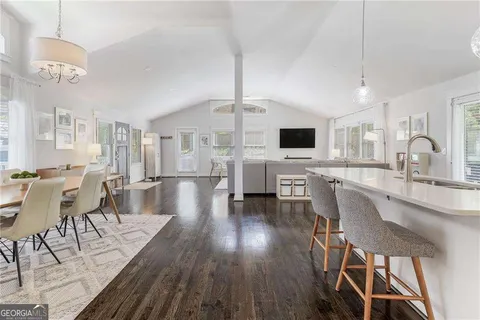 a dining room with wooden floor a chandelier a wooden table and chairs