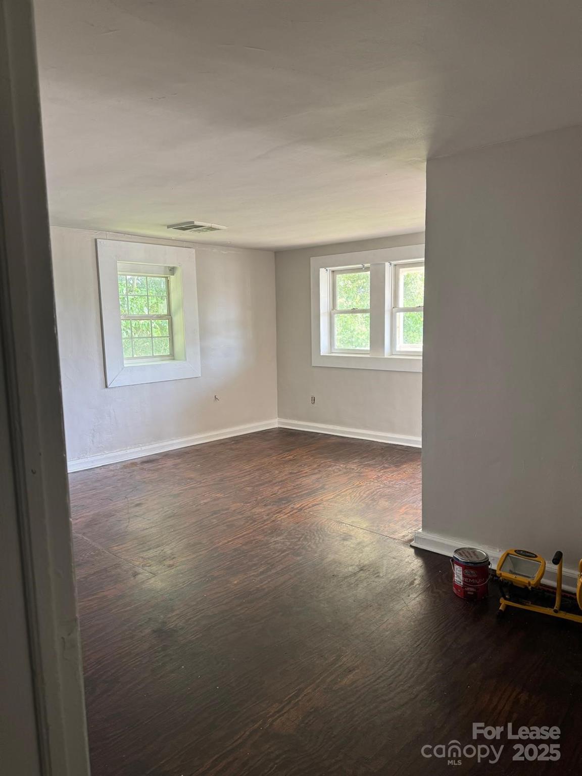 an empty room with wooden floor and windows