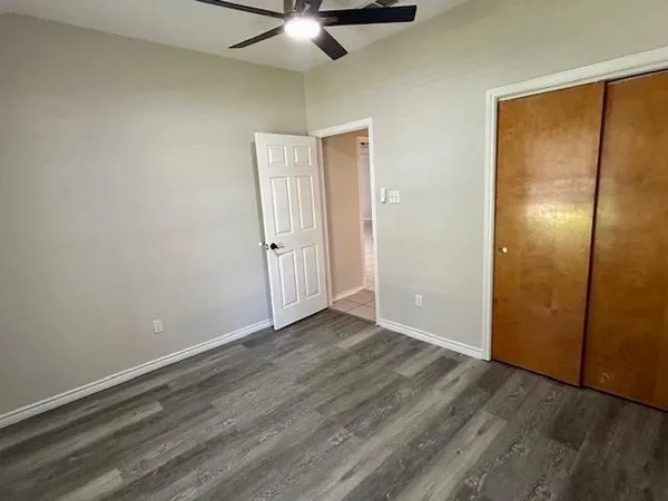 an empty room with wooden floor fan and windows