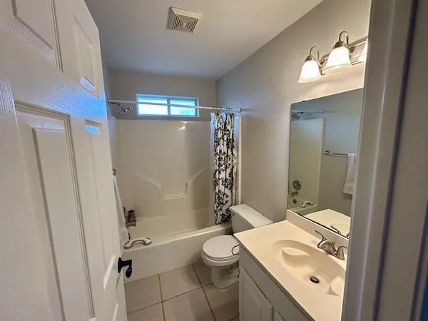 a view of small yard in front of a house with a large tree bed and wooden fence