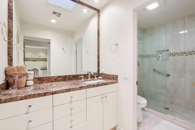 a bathroom with a granite countertop sink a mirror and a shower