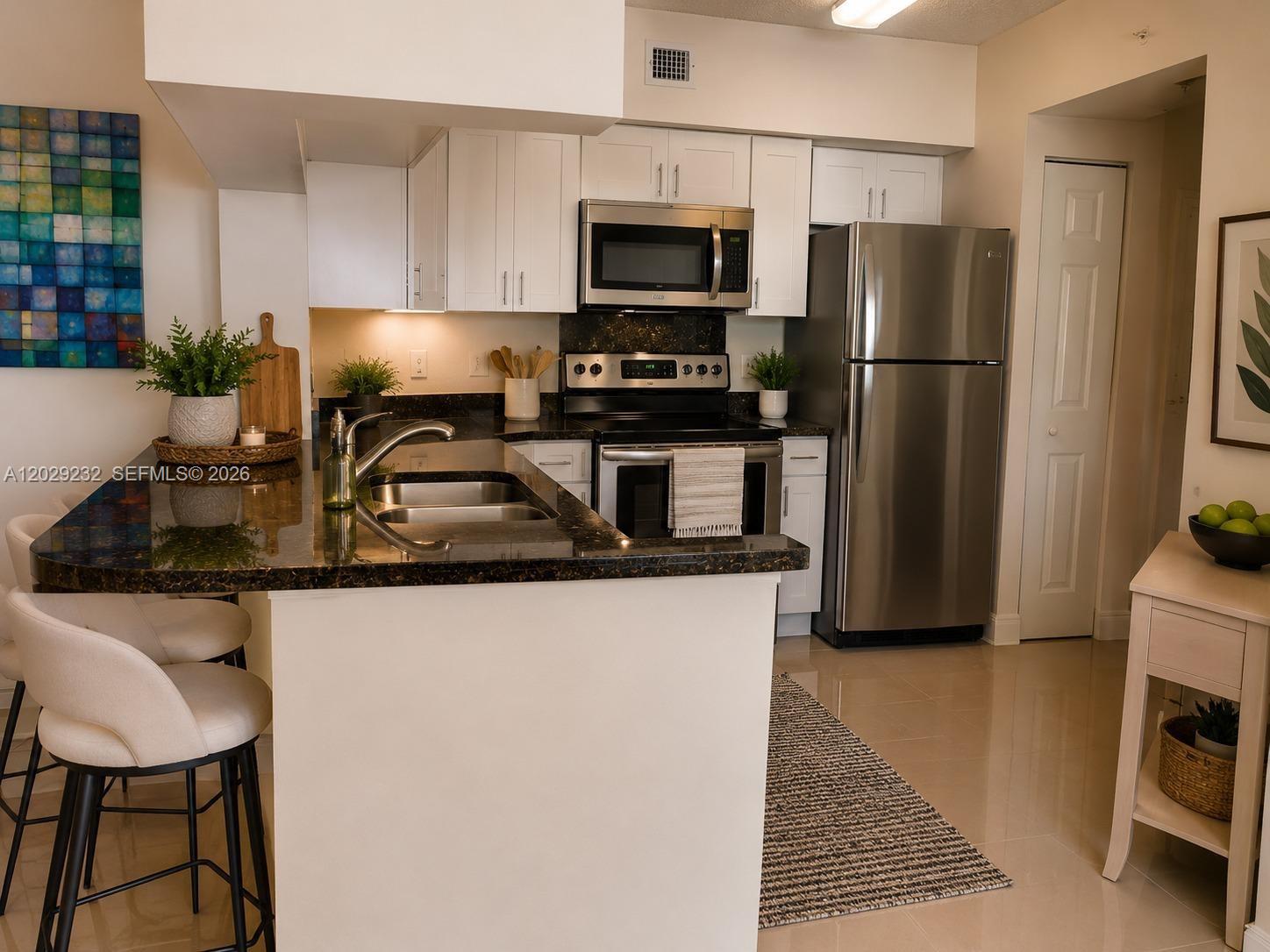 17100 North Bay Road, Unit 1605 Sunny Isles Beach, FL 33160 - Photo 26 of 52 a kitchen with granite countertop a refrigerator stove and sink