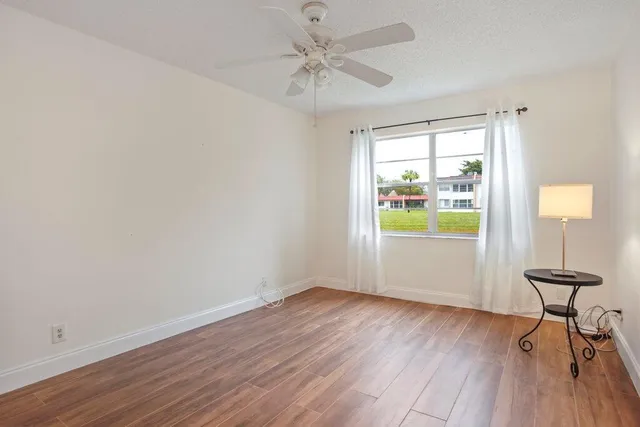 a view of an empty room with a window and wooden floor