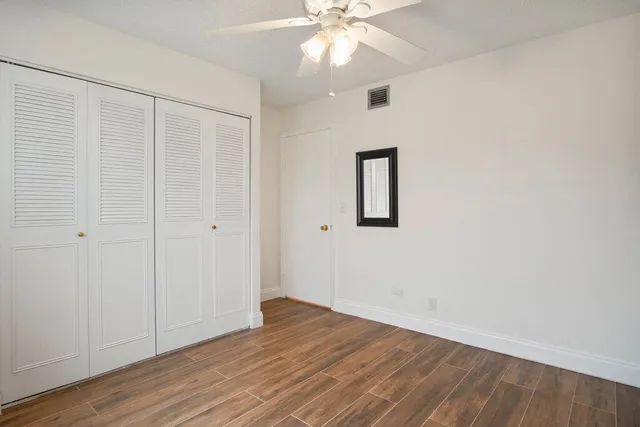 a view of a hallway with wooden floor and a chandelier fan