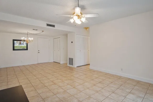 a view of an empty room with a chandelier fan