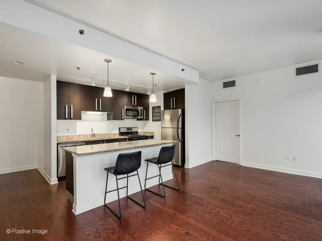 a kitchen with stainless steel appliances a sink a stove a refrigerator cabinets and wooden floor