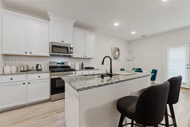 a kitchen with stainless steel appliances granite countertop a sink a stove a microwave and a refrigerator